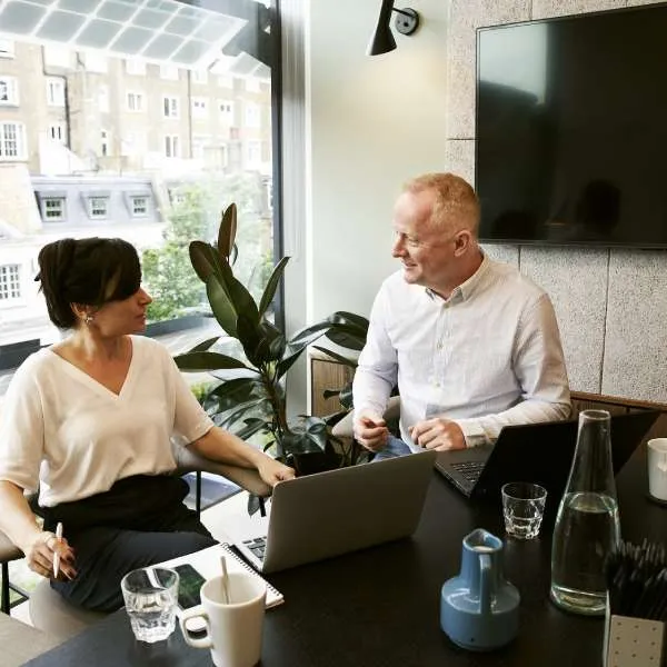 Two colleagues discussing a project at a laptop in a bright office